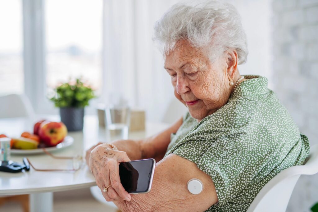 Una signora legge a casa il sensore glicemico con lo smartphone